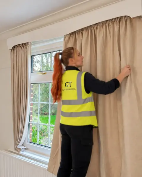 Vickie carefully finishing pencil-pleat curtains during a GT installation